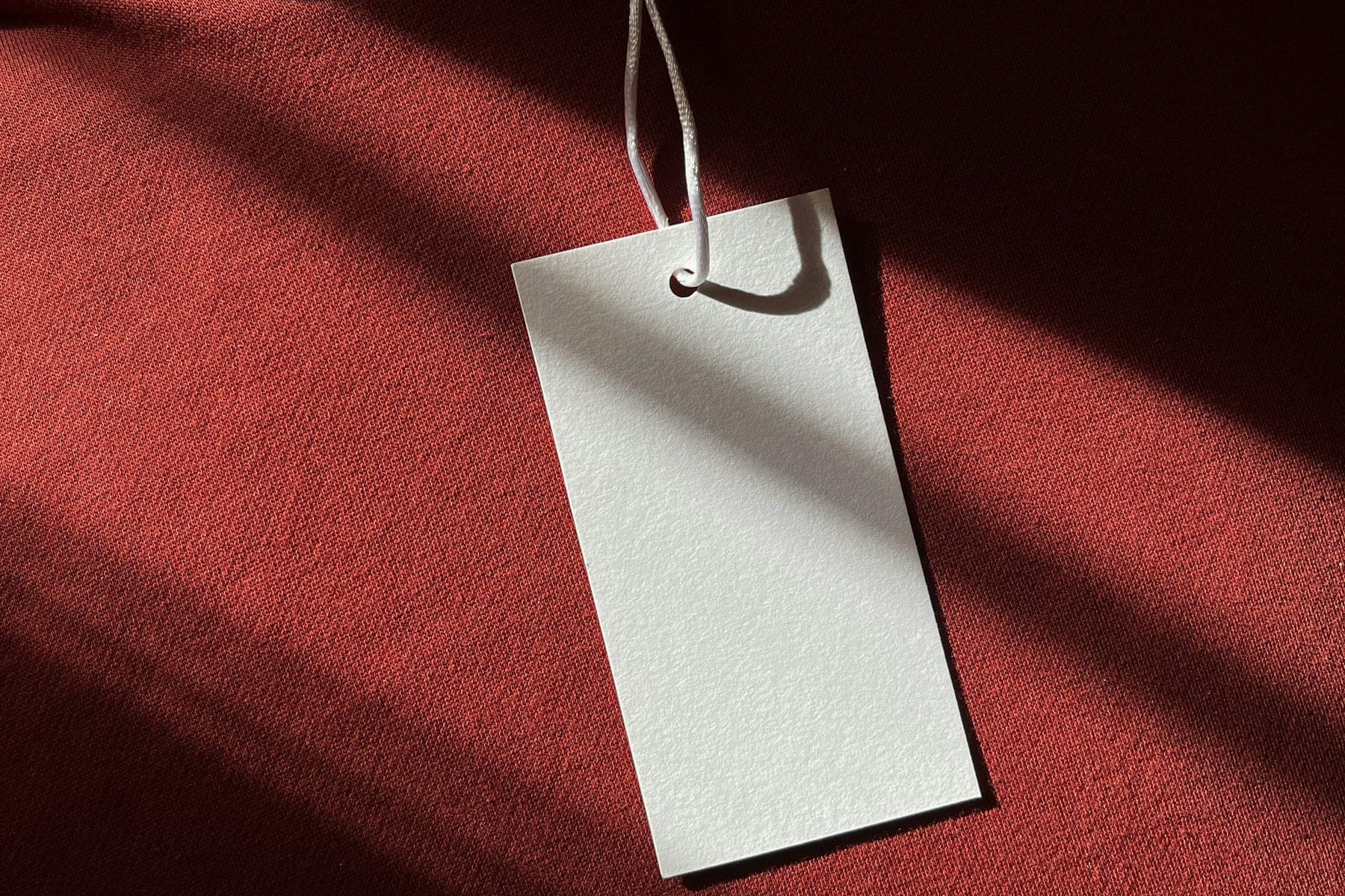 A blank white hang tag on a red garment, ready for a brand