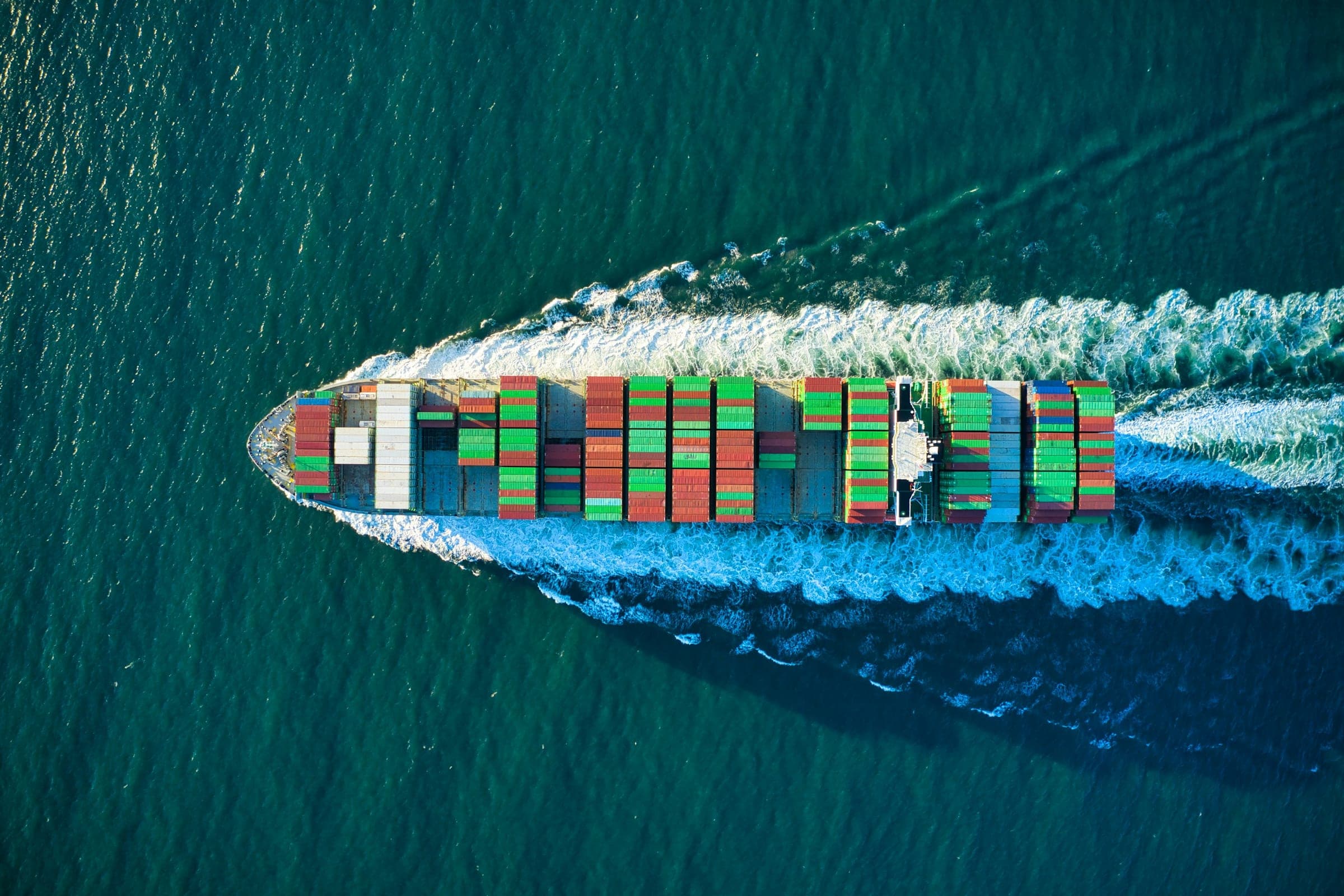 Container ship loaded with cargo crossing the open sea, seen from above