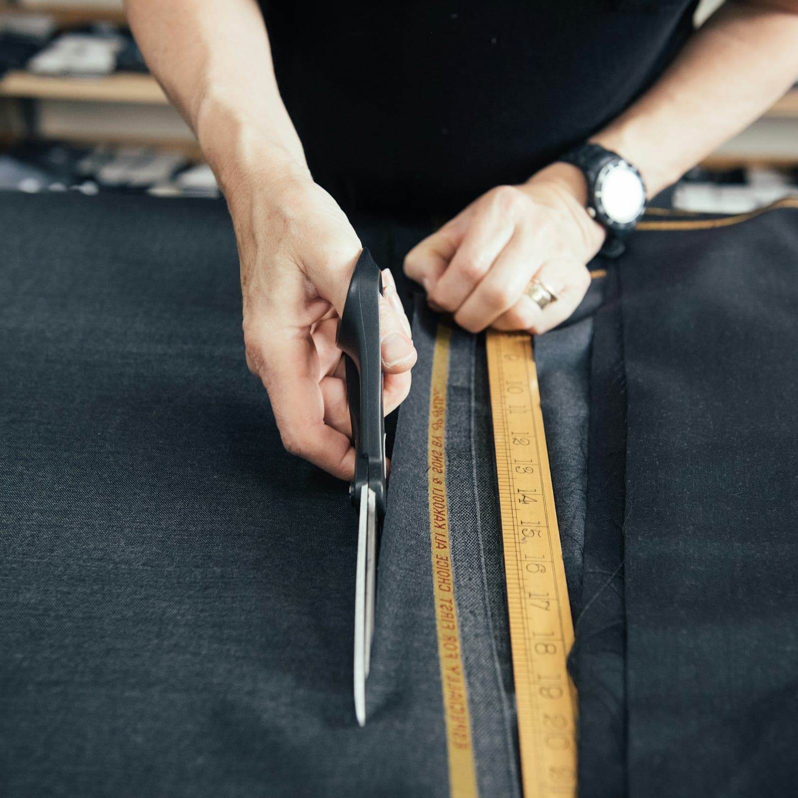 Cutter cutting dark fabric along a ruler with shears