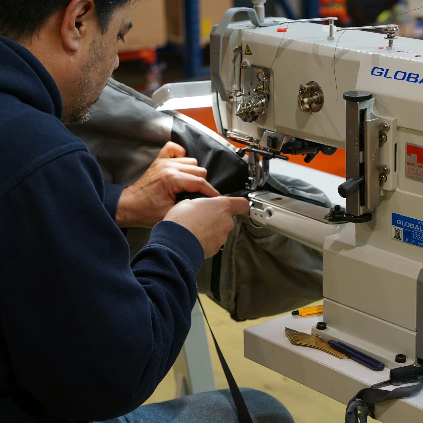 Operator stitching a heavy garment on an industrial sewing machine