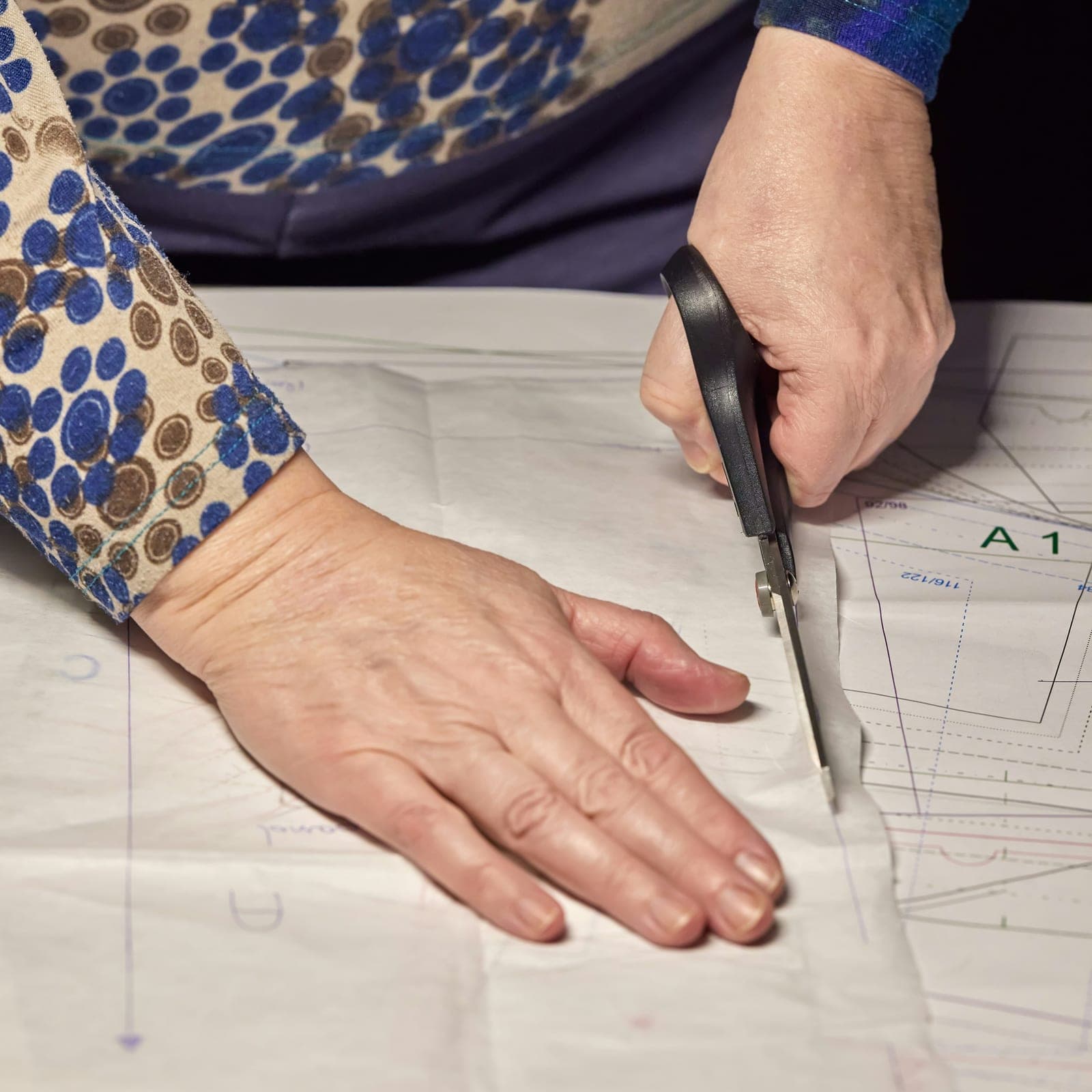 Pattern maker cutting a paper pattern with scissors