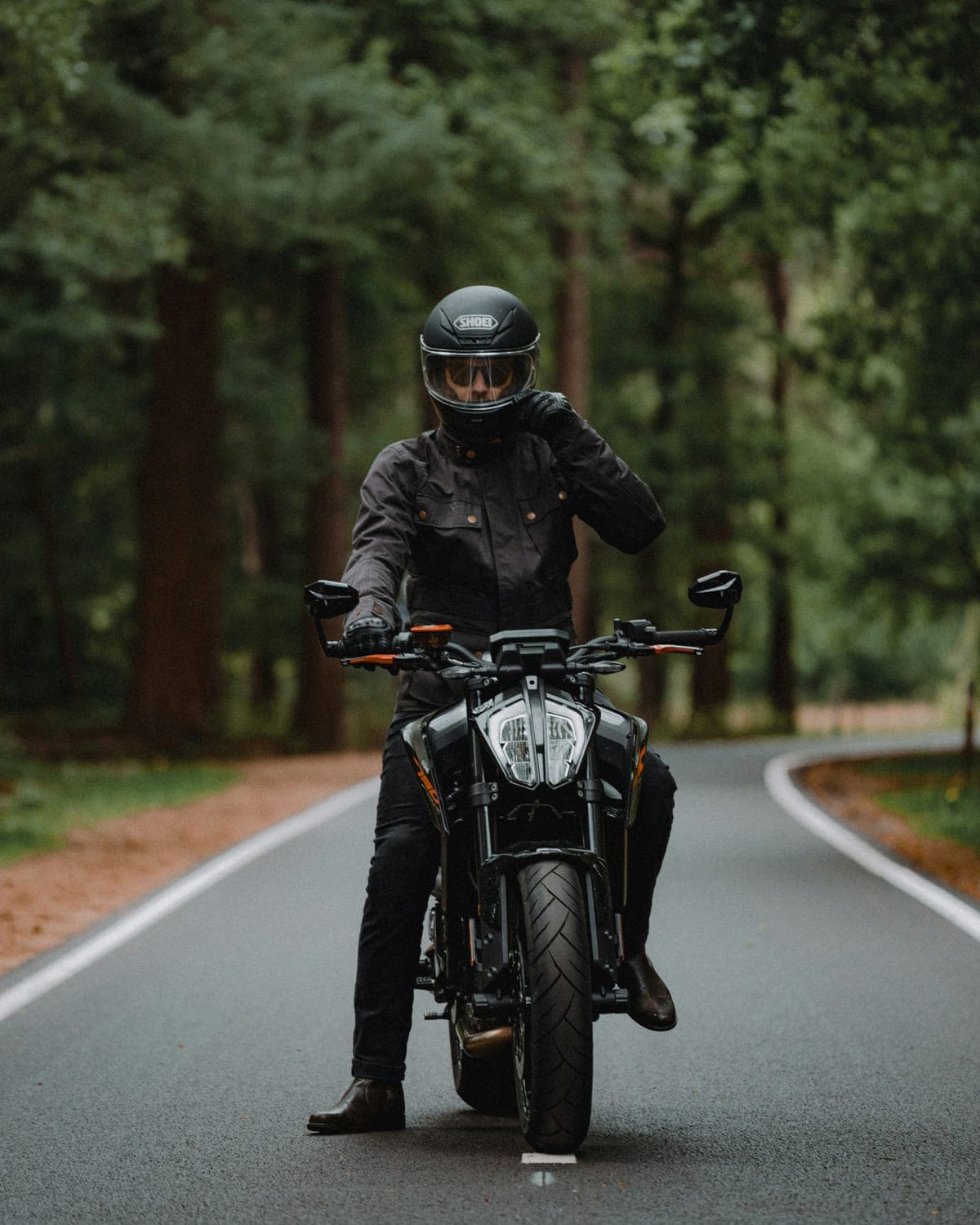 Rider in a helmet and riding jacket on a motorcycle on a forest road
