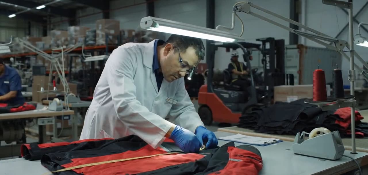 An inspector checking a finished red and black jacket on the inspection table